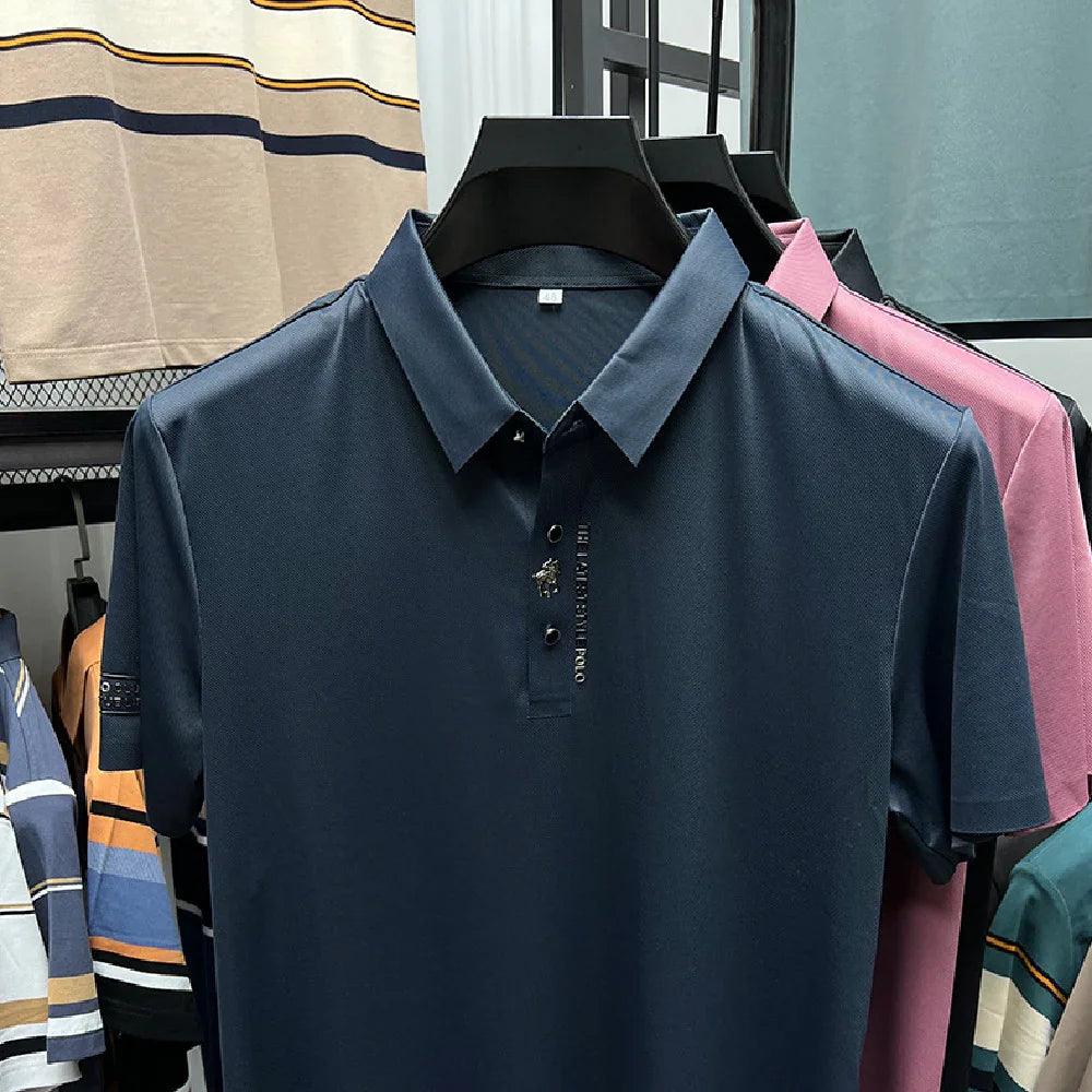 Navy blue men's polo shirt with embroidered logo, displayed on hanger with pink and striped polos in background