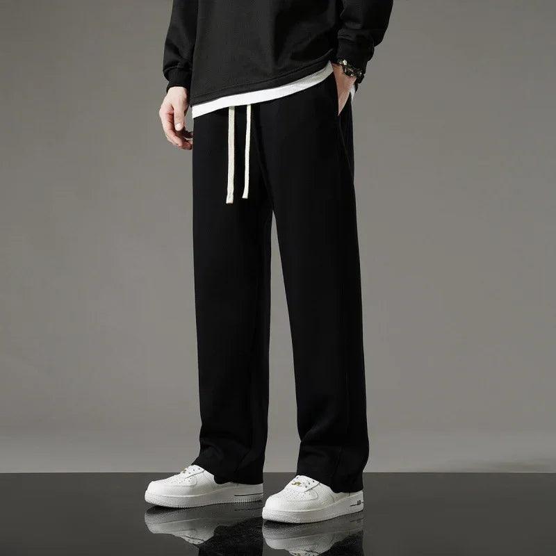 Black relaxed fit joggers with white drawstring, paired with white sneakers for casual comfort wear