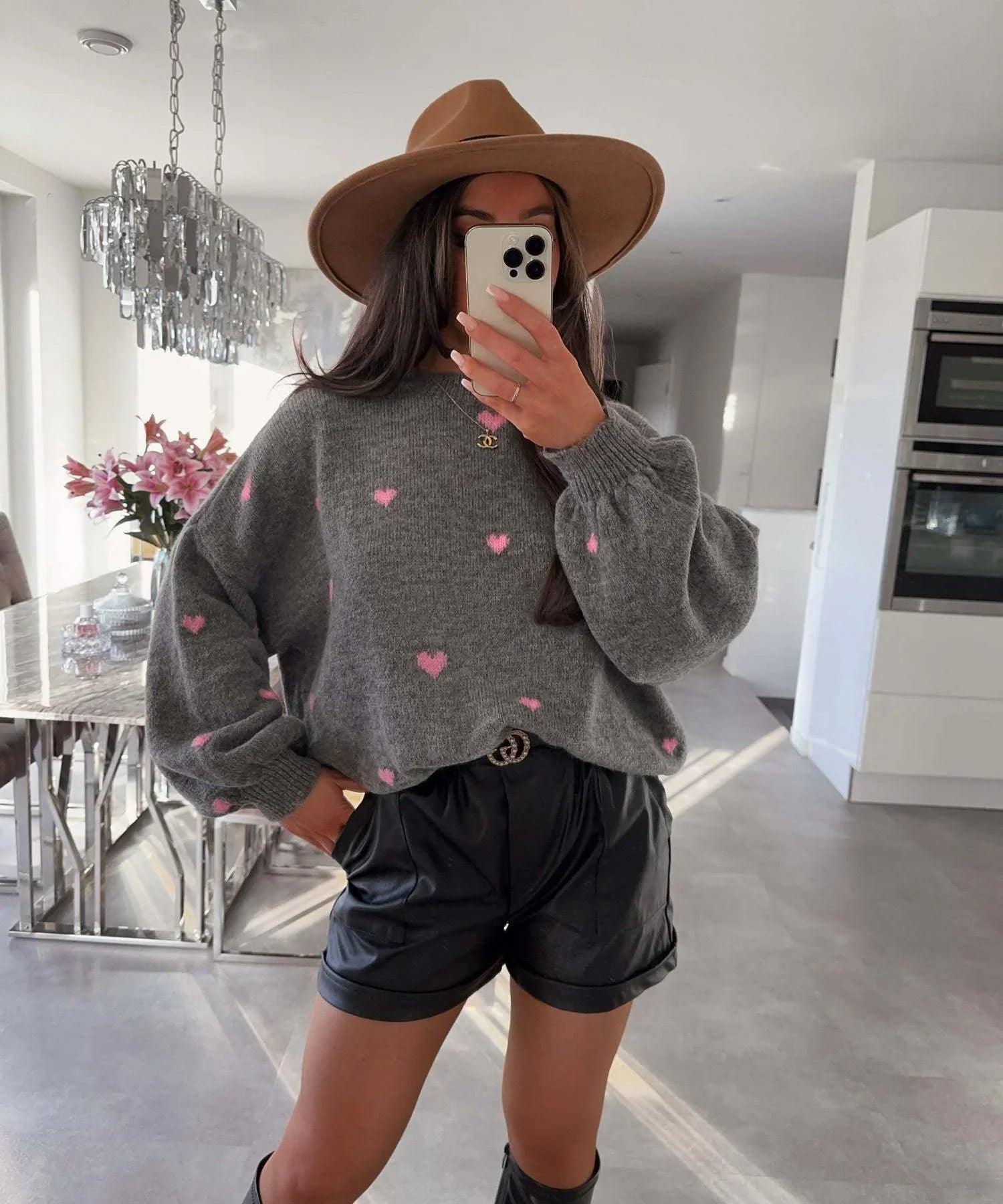 Woman in gray heart-print sweater, black shorts, and brown hat for stylish comfort wear