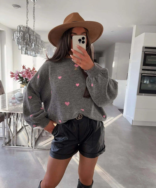Woman in gray heart-print sweater, black shorts, and brown hat for stylish comfort wear