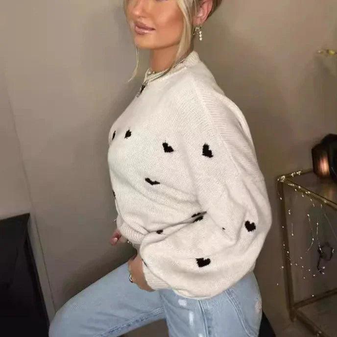 Cream knit sweater with black heart pattern, paired with light wash jeans for cozy everyday style.